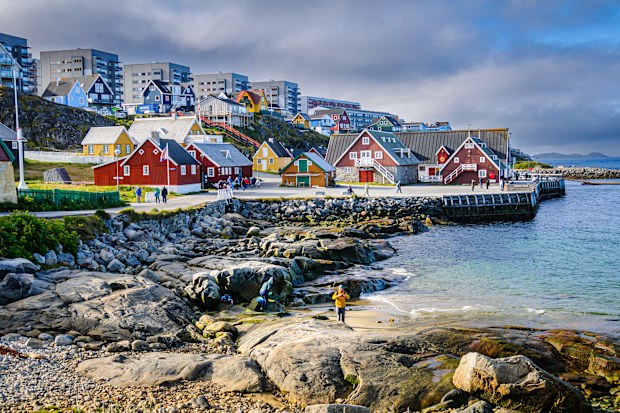 Two people explore the tiny beach on the rocky shore of Nuuk, Greenland on an August morning.