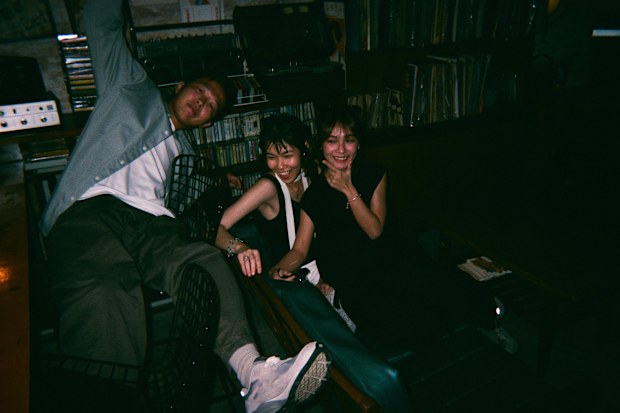 Disposable camera image of playful fun asian chinese friends portrait in retro music record store cafe with fashion clothing