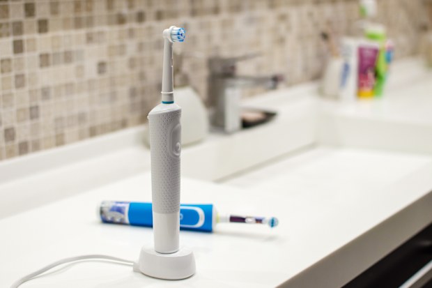 Electric toothbrush on charger stand on bathroom vanity