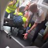 A still from footage of the boy being restrained by a Jetstar worker, passenger Barry Clark and the pilot.