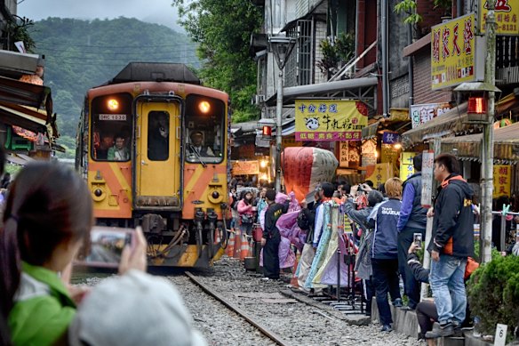 With echoes of a similar scene from Hanoi, Vietnam, a train passes through a narrow street in the town of Shifen, Taiwan.