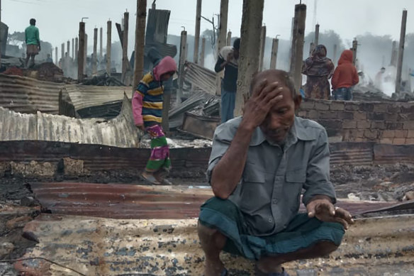 A Rohingya refugee sits by charred remains after the fire in Nayapara Camp in Cox's Bazar.