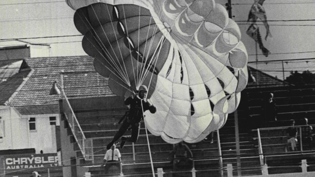 Taking off at 50 m.p.h. on a parachute behind a tow truck, parachutist Ian Handley, 21, of Hornsby, swings into the air over a photographer during a Show preview at the Sydney Showground yesterday... April 3, 1968.