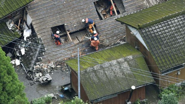 Rescuers work on the rooftop of the house damaged by a landslide in Soo, Kagoshima prefecture,  western Japan, on July 4 last year.