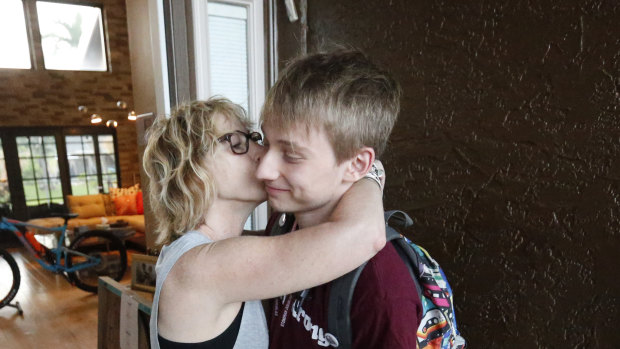 Charlie Shebes, right, 16, a junior at Marjory Stoneman Douglas High School, gets a kiss from his mother Amy as he leaves for school.