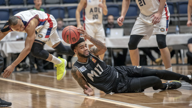 Adelaide’ Adris Deleon and Melbourne United’s DJ Kennedy launch themselves at a mid-court loose ball.