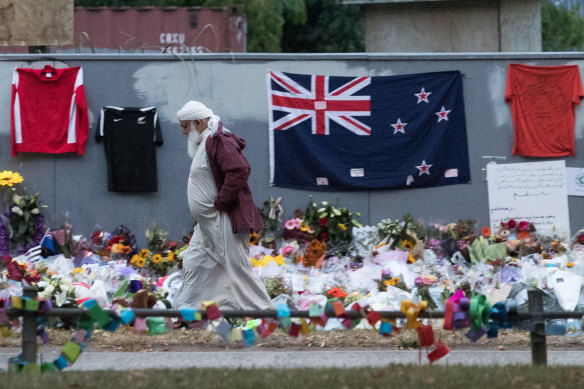 A Muslim man walks past a makeshift memorial on the walls surrounding the Al Noor Mosque following the Christchurch attack.