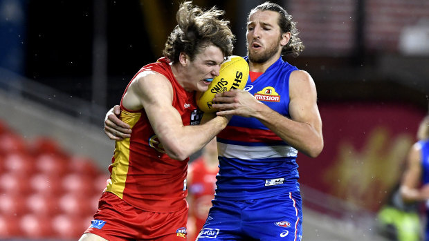 Charlie Ballars of the Suns faces a fierce attack from Bulldogs captain Marcus Bontempelli.