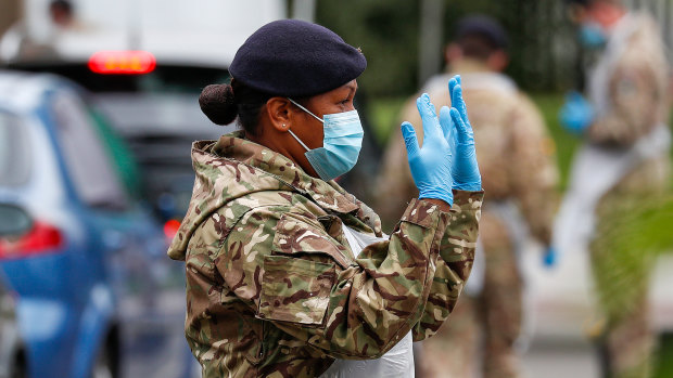 A member of the British armed forces directs a driver at a COVID-19 mobile testing centre in Leicester.