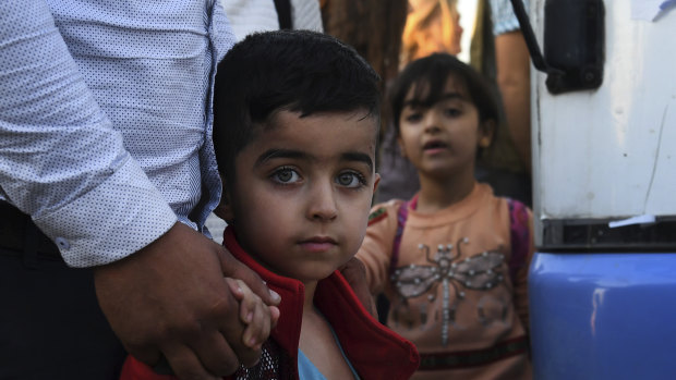 A Syrian boy holds his father's hand as he arrives at the Bardarash refugee camp.