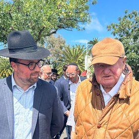Adass Israel board member Benjamin Klein (left) speaks to businessman Lindsay Fox outside the synagogue destroyed by fire.