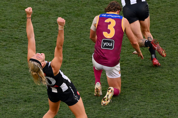 Darcy Moore raises his arms in the air to celebrate Collingwood’s win, while his opponent Joe Daniher is dejected on the final siren.