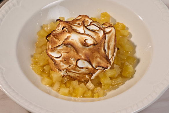 Coconut bombe Alaska is moated with diced pineapple.