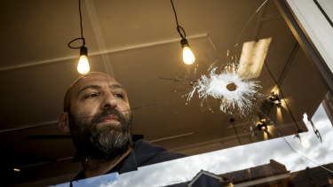 Cafe owner Fidel Takla surveys the bullet holes at his cafe.