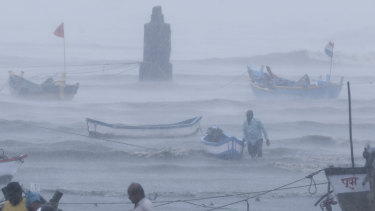 A fisherman tries to move a boat to safer ground on the Arabian Sea coast in Mumbai on Monday.