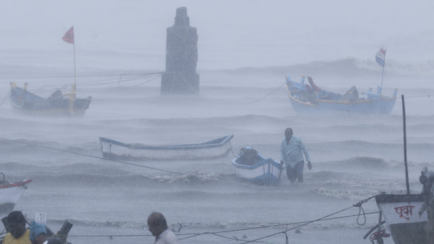 A fisherman tries to move a boat to safer ground on the Arabian Sea coast in Mumbai on Monday.