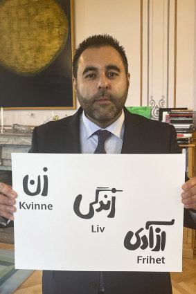Iranian-born speaker of the Norwegian parliament Masud Gharahkhani holds a poster, saying in Iranian and Norwegian “Woman, life, freedom”, in his office in Oslo, Norway, minutes after the announcement.
