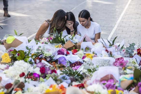 Three young women embrace at the makeshift shrine to the victims of the stabbings.