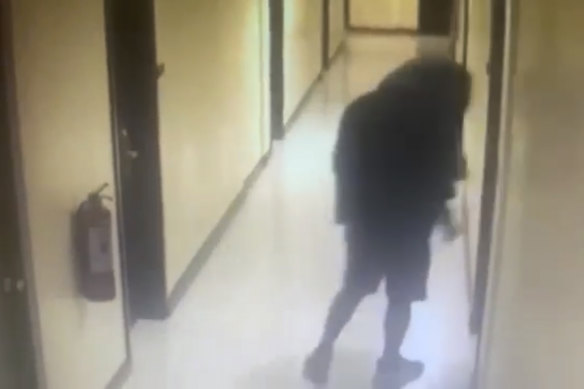A man, whom police identified as a suspect, walks along a hallway before entering a room at the hotel.