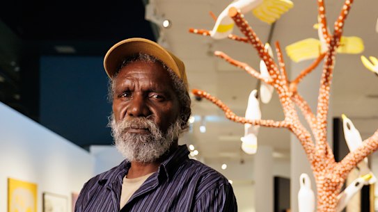 Keith Wikmunea with his work Ku’, Theewith & Kalampang: The White Cockatoo, Galah and the Wandering Dog.