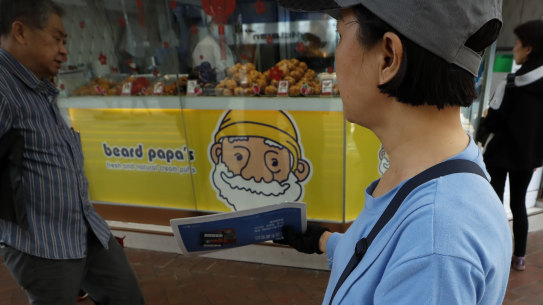 A vendor gives out copies of newspaper with a headlines about the coronavirus in Hong Kong.