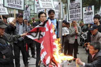 Protesters burn a Japanese rising sun flag in front of the Japanese embassy in Seoul, South Korea, in 2013.