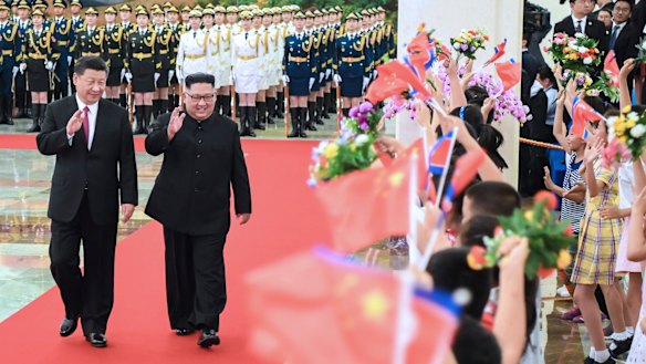Xi Jinping and Kim Jong-un walk together during a welcoming ceremony for Kim at the Great Hall of the People in Beijing on Tuesday.