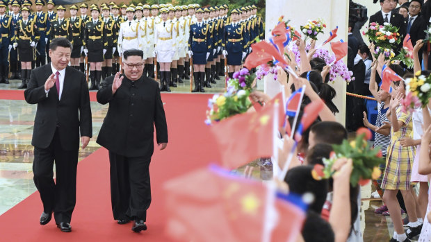 Xi Jinping and Kim Jong-un walk together during a welcoming ceremony for Kim at the Great Hall of the People in Beijing on Tuesday.