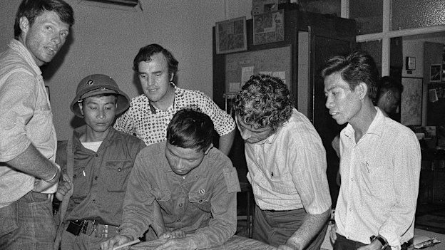 The last three staffers in The Associated Press’ Saigon bureau, reporters Matt Franjola (left) Peter Arnett (rear) and George Esper (second from right) are joined by two North Vietnamese soldiers and a member of the Viet Cong on the day of South Vietnam’s surrender, April 30, 1975. One of the soldiers is showing Esper the route of his final advance into the city.