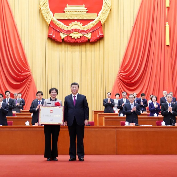 Xi Jinping presents an award to a village in Anhui province for being a role model in fighting poverty, in Beijing in February 2021.