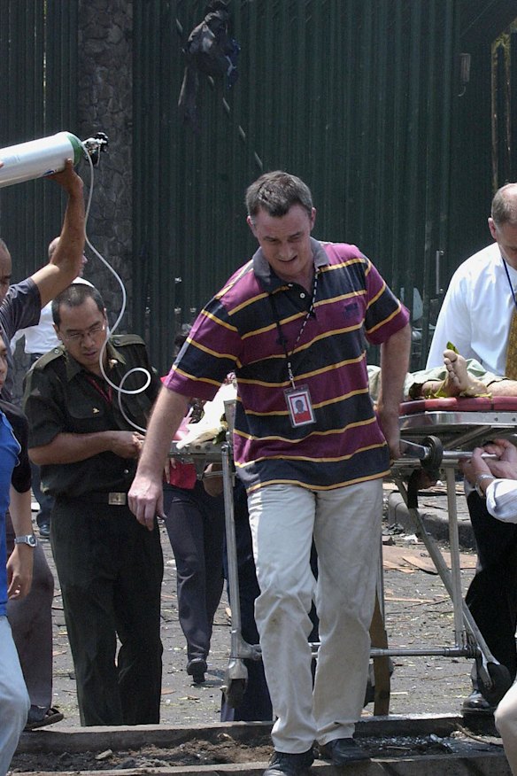 Grant Dooley (centre) helps carry embassy gardener Suryadi to an ambulance.
