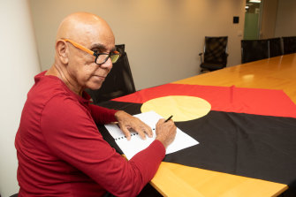 Luritja artist and activist Harold Thomas signs the agreement with the federal government.