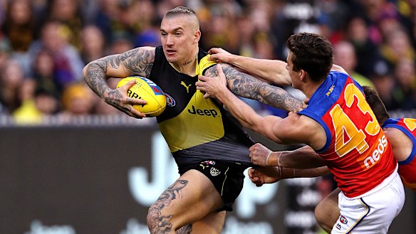 Storming home: Richmond's Dustin Martin holds off a pair of hungry Lions.