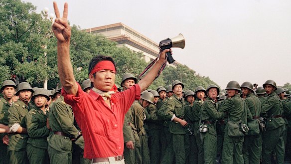 A student pro-democracy protester flashes victory signs to the crowd the day before the massacre.