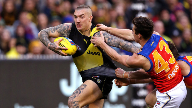 Storming home: Richmond's Dustin Martin holds off a pair of hungry Lions.
