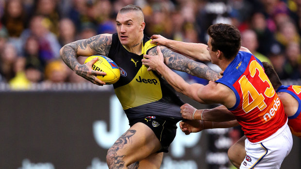 Storming home: Richmond's Dustin Martin holds off a pair of hungry Lions.