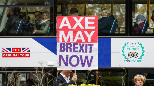 Tourists watch a pro-Brexit campaigner holding a placard saying "Axe May Brexit Now" from a tour bus in Westminster, London, on Friday.