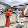 A Spanish passenger is sprayed with disinfectant by Spanish government officials before boarding a plane after disembarking from the hantavirus-stricken cruise ship on Sunday.