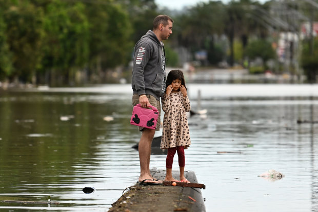 A father and daughter inspect a flooded Lismore street in March 2022.