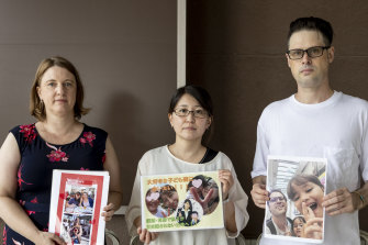Catherine Henderson, Izumi Dobashi and Scott McIntyre hold photos up of their children. 