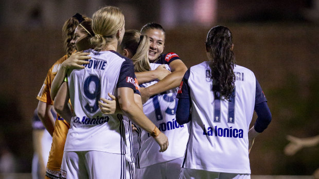 Victory players celebrate their premiership triumph after beating Perth Glory on Friday night.