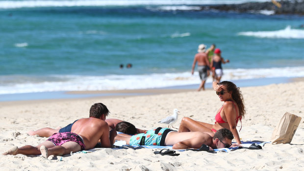 People relax at Burleigh Heads beach on the Gold Coast on Saturday after COVID-19 restrictions eased at midnight.
