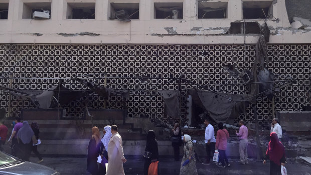 People survey the aftermath of a fiery car crash outside the National Cancer Institute in Cairo.