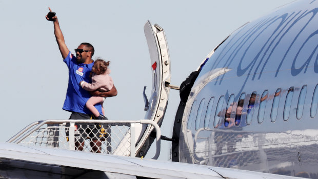 Liam Ryan waves farewell with his daughter in his arms as he and the West Coast Eagles squad and support staff board a flight to the Gold Coast for the resumption of the 2020 AFL season.