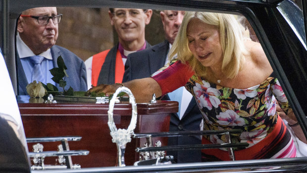 Kerri-Anne Kennerley places her hand on the casket following the funeral for her husband John Kennerley.