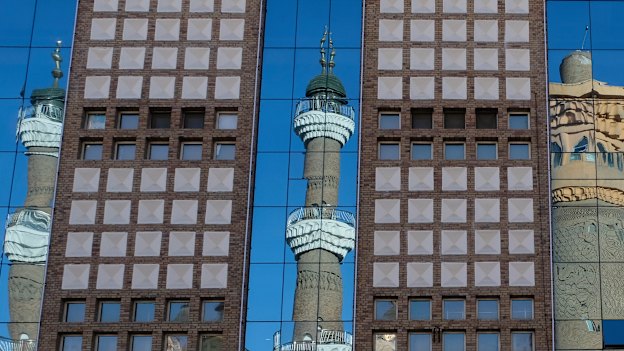 The minarets of the Urumqi International Grand Bazaar Mosque are reflected on nearby building. Taking pictures of mosques, government buildings, and police is prohibited in Urumqi, a local police officer tells us.