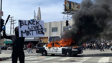 Protesters set fire to a police vehicle on the streets of Los Angeles on May 30.