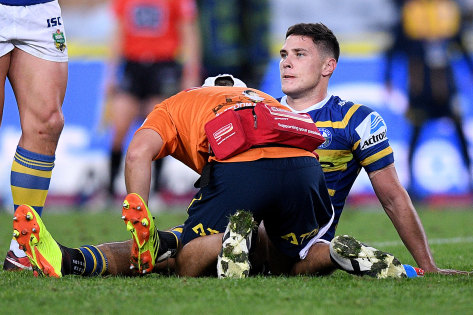 Down and out: Mitchell Moses receives treatment before leaving the field with a knee inury.