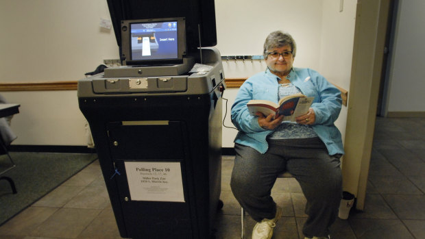 Election judge Carylon Richards reads a book as she waits for voters at the Miller Park Zoo during the Illinois primary on Tuesday.
