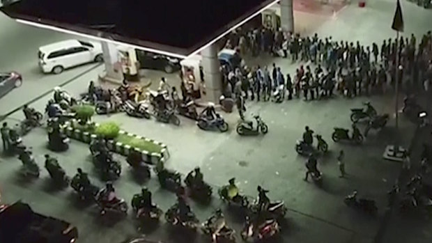 Long queues lead out from a petrol station in the earthquake and tsunami-devastated area of Palu.